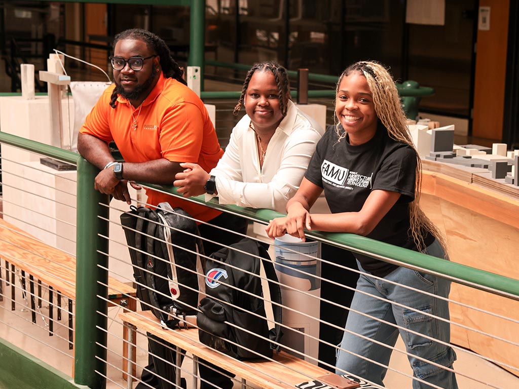 three smiling students in architecture building