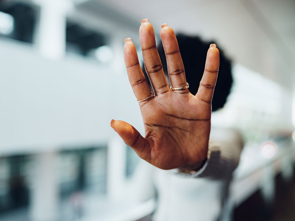 Person holding their hand up in a stop position