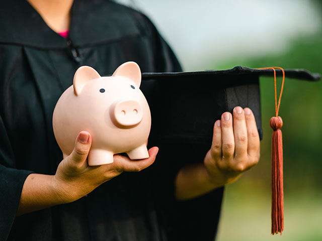 College grad holding piggy bank