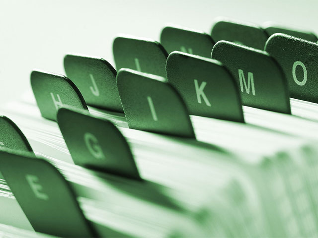   A close-up of green and black 'letter' tabs on a contact directory, representing alphabetical organization.