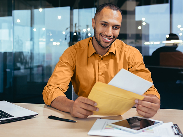 Happy african american businessman reading letter from received from large envelope