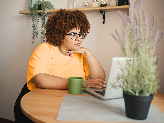 ounfg woman standing at table and using laptop