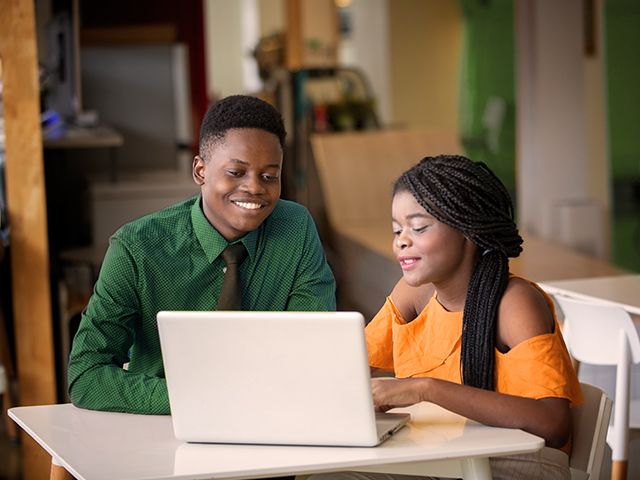man and woman looking at laptop in study lounge