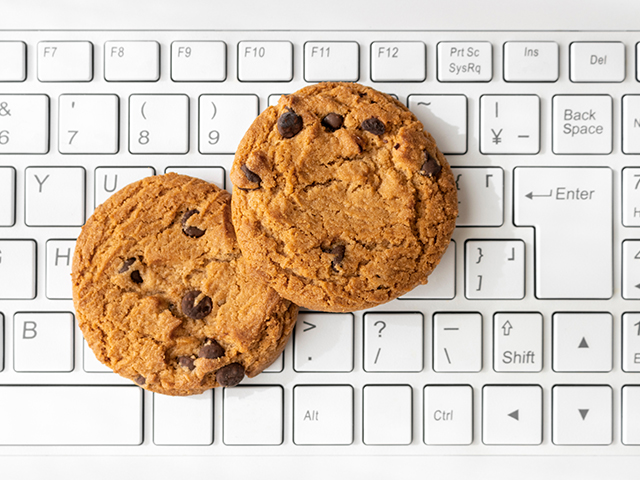 two chocolate chip cookies sitting on top of a white keyboard