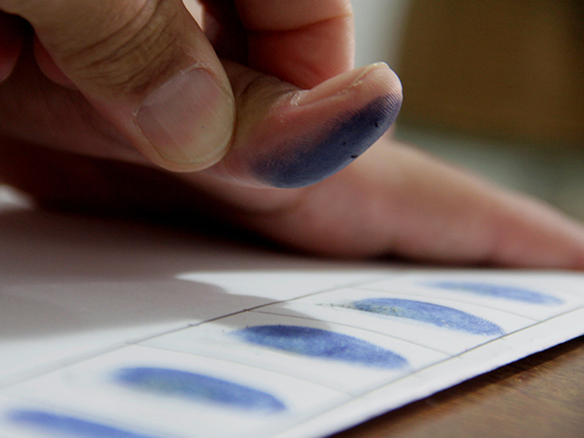 close up of hand collecting fingerprints of a piece of paper