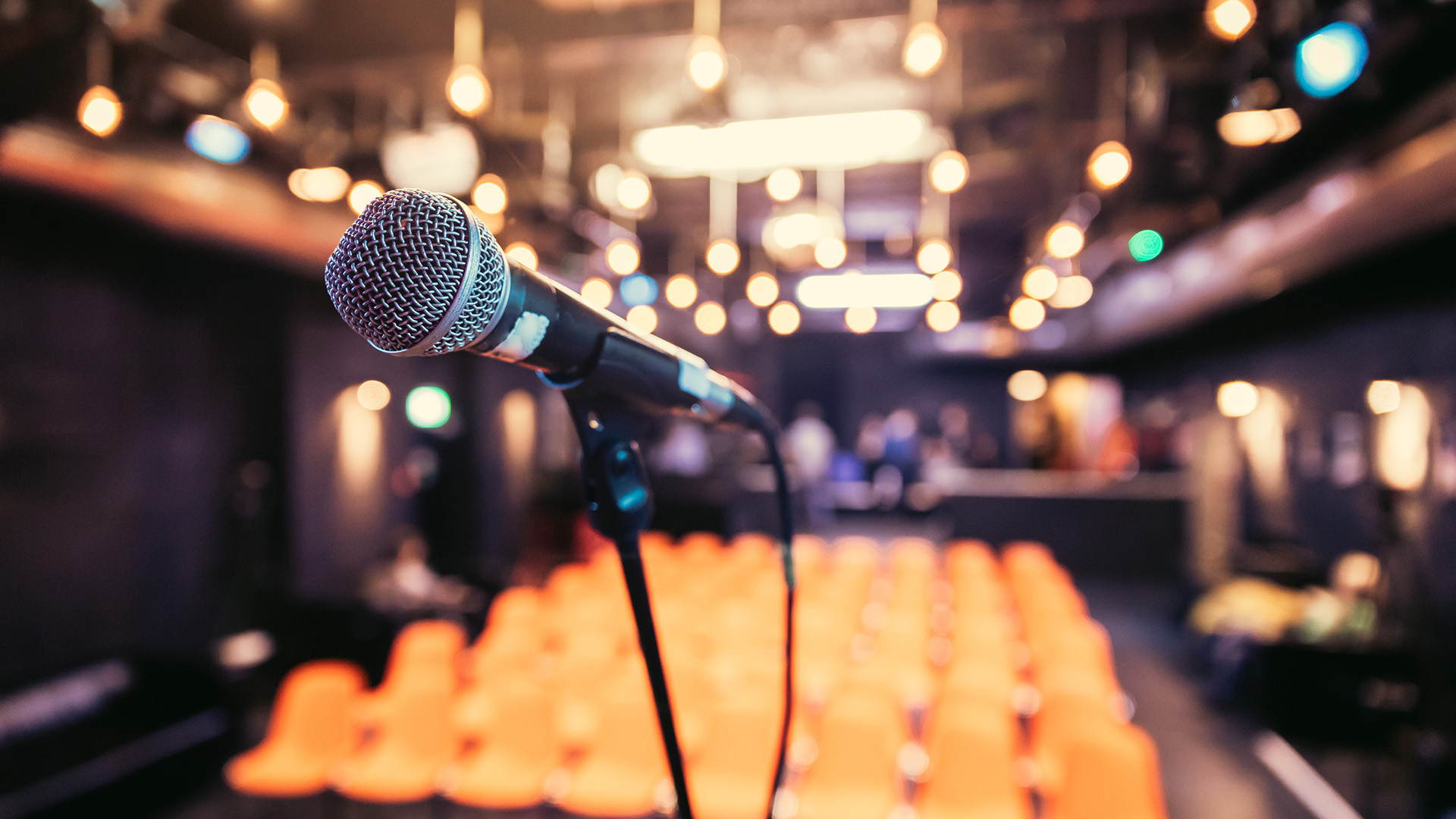 Close up of microphone stand, empty seats in the blurry background