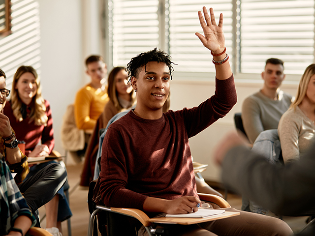 Student in classroom rasing his hand