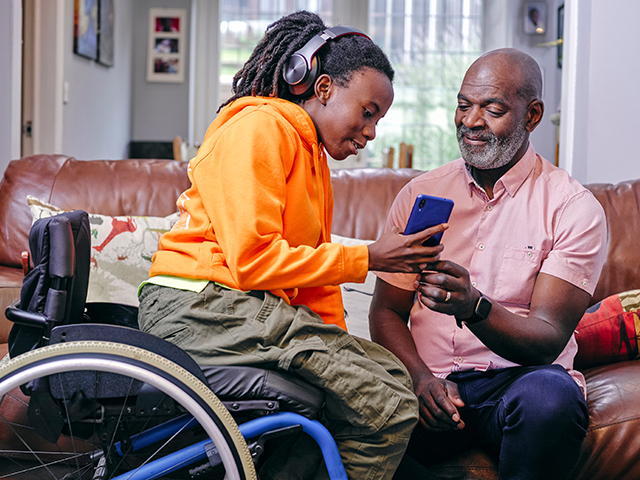 close up shot of African american Girl in wheelchair and grandfather using phone