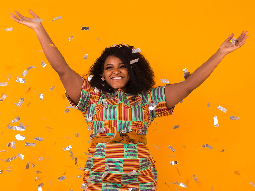 young woman dancing with big smile throwing confetti