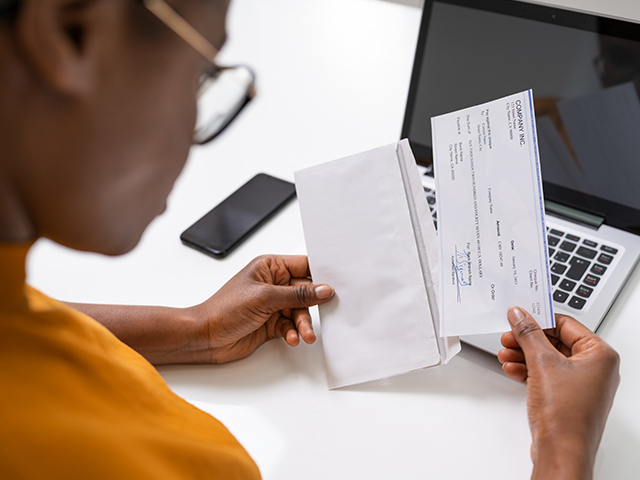 An African American young woman putting a cheque in an envelope