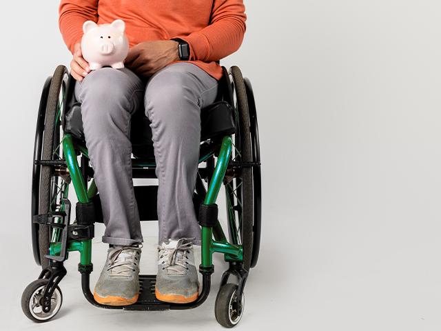 person in a wheelchair holding a pink piggy bank